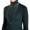 Woman wearing black turtleneck and 7 chain necklaces showing the different measurements in inches of each chain from 15 to 34 inches