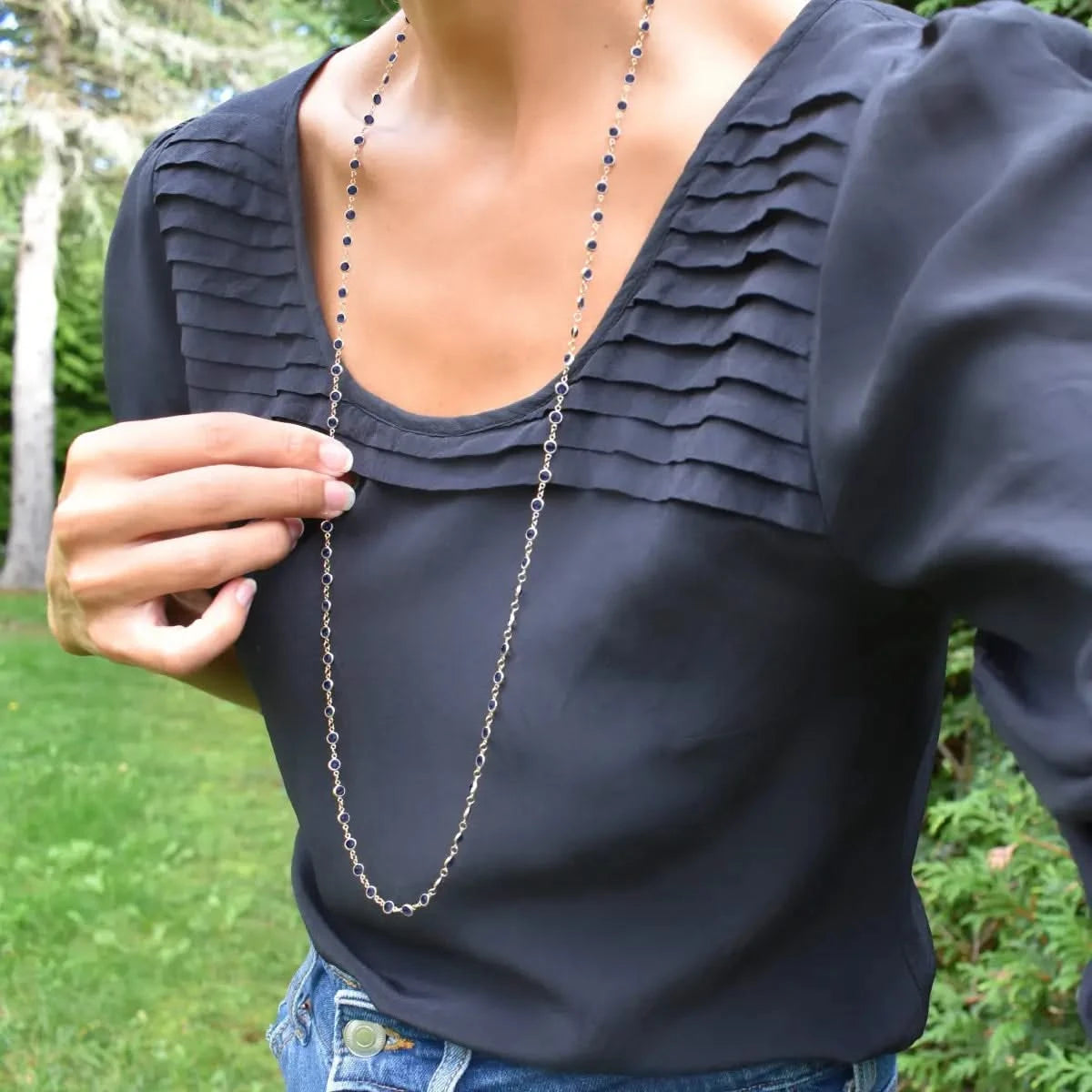 Woman wearing a Newport Wrap necklace featuring 4 mm briolette cut sapphires bezel set in 14k yellow gold