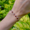 A wrist wearing a Newport Grand Garnet bracelet featuring a continuous strand of 6mm briolette cut, bezel set gemstones.