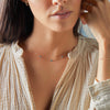 Woman wearing a Bayberry birthstone necklace featuring three 4 mm briolette Nantucket blue topaz bezel set in 14k gold