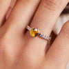 Woman's finger adorned with a 14k gold Rosecliff Grand Ring with a 6 mm round, briolette-cut Citrine and eight 2 mm round-cut Diamonds.