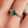 A hand adorned with the Rosecliff Grand Ring, featuring a mesmerizing emerald flanked by accent diamonds, epitomizing the unique and timeless allure of emerald engagement rings.