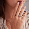 Woman's hand adorned with a 14k gold Rosecliff Grand Ring, featuring a 6 mm round, briolette-cut Blue Topaz and eight alternating 2 mm round-cut Diamonds.