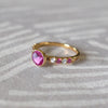 Woman showcasing a 14k gold Rosecliff Grand Ring with a 6 mm briolette-cut Pink Sapphire  and eight alternating 2 mm round-cut Diamonds and Pink Sapphires.