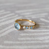 4k gold Rosecliff Grand Ring with a 6 mm briolette-cut Blue Topaz and eight alternating 2 mm round-cut Diamonds and Blue Topazes.