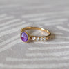 Woman's hand wearing a 14k gold Rosecliff Grand Ring with a 6 mm briolette-cut Amethyst and eight 2 mm round-cut Diamonds.