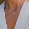 Woman with a Rosecliff open circle necklace with sixteen alternating pink sapphires & diamonds prong set in 14k gold