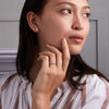 Woman wearing a Rosecliff stackable ring featuring eleven alternating 2mm pink sapphires and diamonds prong set in 14k gold