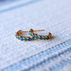 Pair of Rosecliff huggie earrings in 14k yellow gold, each featuring nine alternating 2mm emerald and sapphire gemstones.
