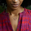 Woman wearing a Rosecliff Heart Necklace featuring twenty alternating garnets and diamonds prong set in 14k yellow Gold