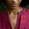 Woman wearing a Rosecliff Heart Necklace featuring twenty faceted round cut rubies prong set in 14k yellow Gold