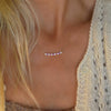Woman wearing a Rosecliff bar necklace with alternating 2 mm pink sapphires, white topaz & amethysts prong set in 14k gold