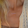 Women wearing a Rosecliff bar necklace with eleven alternating 2 mm faceted pink sapphires & diamonds prong set in 14k gold