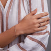 Woman adorned with a Rosecliff small open circle ring featuring twelve alternating 2 mm garnets and diamonds prong set in 14k gold