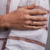 Woman's hand wearing a Rosecliff small open circle ring featuring twelve alternating 2 mm rubies and diamonds prong set in 14k gold