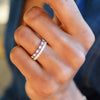 Woman wearing a gold De-Lovely Rosecliff stackable ring featuring 11 alternating pink sapphires, white topaz and amethysts