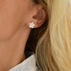 Woman's ear wearing a Greenwich Flower earring featuring five 4mm white topaz gemstones and one 2.7mm center diamond.