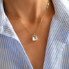 Woman wearing an Adelaide paper clip chain and a Warren pendant with an emerald cut bezel set white topaz gemstone in 14k gold