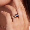 Woman showcasing a 14k yellow gold Warren Horizontal Garnet Ring, featuring an emerald-cut 8 x 10mm Nantucket Blue Topaz, hand-set horizontally in a 14k-gold bezel.