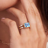 Woman's hand adorned with a 14k yellow gold Warren Horizontal Nantucket Blue Topaz Ring, showcasing an emerald-cut 8 x 10mm Nantucket Blue Topaz, hand-set horizontally in a 14k-gold bezel.