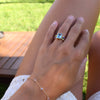 A woman wearing a Personalized Rainbow Warren Vertical Ring in 14k gold with eight colorful accent gems on both sides, paired with a Bayberry 7 Birthstone Bracelet.