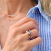 A woman wearing a Personalized Rainbow Warren Horizontal Ring in 14k gold with eight colorful accent gems on both sides.
