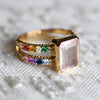 Warren ring with rainbow patterned, prong set accent gemstones, featuring a 10 x 8mm bezel set Rose Quartz center stone.