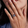 Woman wearing a 14k yellow gold Warren Vertical Ring with accent diamonds featuring one 10 x 8 mm emerald cut bezel set Alexandrite.