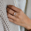 Woman wearing a Warren ring in 14k yellow gold with accent diamonds featuring one 10 x 8 mm emerald cut bezel set rose quartz