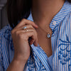 Woman showcasing a 14k yellow gold Warren Pendant and matching Vertical Aquamarine Ring, featuring one 10 x 8 mm emerald cut, bezel set Aquamarine in 14k Gold.