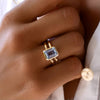 Woman's hand wearing a 14k yellow gold Warren Vertical Aquamarine Ring, showcasing one 10 x 8 mm emerald cut, bezel set Aquamarine in 14k Gold.