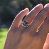 Woman showcasing a 14k yellow gold Warren Vertical Ring with accent diamonds featuring one 10 x 8 mm emerald cut bezel set Alexandrite.