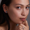 Woman adorned with Greenwich Birthstone Earrings in 14k Gold featuring four 4 mm faceted round cut, prong set Alexandrites and one 2.1 mm Diamond. 