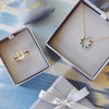 Two opened signature gift boxes featuring a Warren ring with accent stones and Rosecliff Circle necklace in 14k yellow gold.
