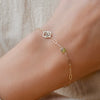 Wrist wearing a personalized Zodiac & Birthstone Adelaide Mini bracelet featuring a cutout zodiac charm & 4mm gemstone.