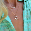 Woman wearing a Rosecliff Diamond bar necklace and a 12.5mm Flat Leo pendant on a 1.17mm cable chain in 14k yellow gold.