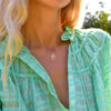 A blonde woman wearing a 16.79mm x 11.38mm cutout Hamsa pendant on a 1.17mm classic cable chain.