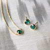 A pair of Grand Stud earrings and a Grand 1 Birthstone necklace, both featuring 6mm briolette cut, bezel set emeralds.