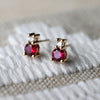 Pair of Greenwich Solitaire earrings in 14k yellow gold, each featuring one 4mm prong set ruby and 2.1mm prong set diamond.