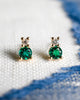 Pair of Greenwich Solitaire earrings in 14k yellow gold featuring one 4mm faceted round cut emerald & one 2.1mm diamond.