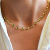 Woman wearing a Newport Grand Peridot necklace featuring 6mm briolette cut, bezel set gemstones in 14k yellow gold.