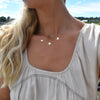 Woman wearing a layered personalized Classic 6 Birthstone necklace and a personalized double-spaced 3 Letter necklace.