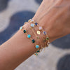 Woman wearing two personalized Newport Grand bracelets, a MAMA bracelet, & a personalized Classic 5 birthstone bracelet.