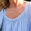 Woman wearing a Grand 14k yellow gold 1.17 mm cable chain necklace featuring one 6 mm briolette cut bezel set garnet