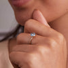 Woman's hand adorned with a stunning Nantucket Blue Topaz Grand Ring featuring a 6mm briolette-cut gemstone in a 14k gold bezel, ideal for stacking or gifting.