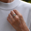 Woman's hand wearing three stacked Grand rings featuring a single 6mm Nantucket blue topaz, emerald, and white topaz.