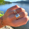 Woman's hand graced with assorted Haverhill rings, including a Warren ring in 14k yellow gold with a vertically placed, bezel-set 10x8mm emerald-cut aquamarine.