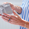 A woman holds a luxurious pouch in a Haverhill signature box, finished with a satin ribbon, while wearing personalized Rosecliff and Warren Vertical rings on her hands.