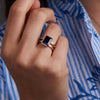 Woman showcasing a 14k yellow gold Warren Vertical Sapphire Ring, featuring one 10 x 8 mm emerald cut, bezel set Sapphire.