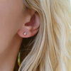 Close-up of a woman's ear wearing a Providence White Topaz stud earring featuring one 2x4mm baguette cut, prong set gemstone.